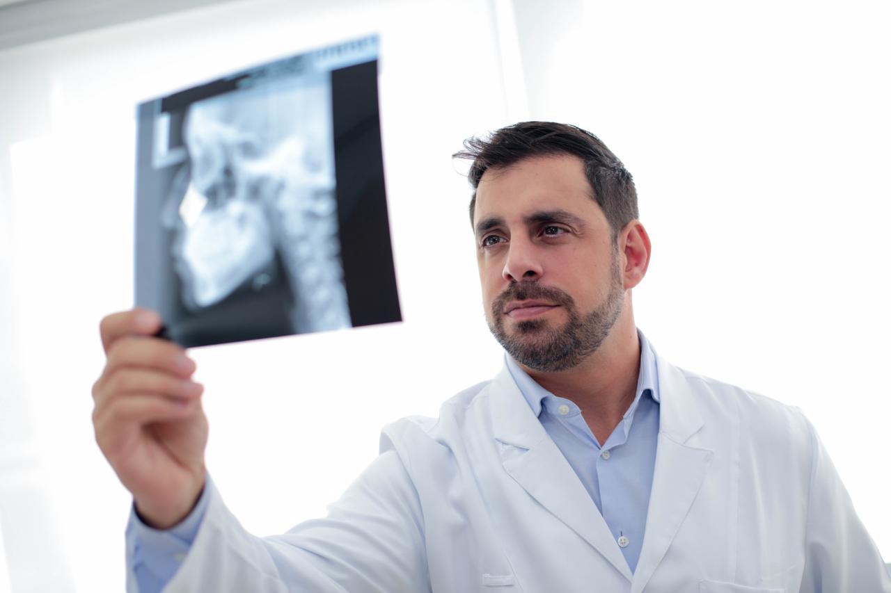 Dr. Luiz Guilherme observando uma radiografia no consultório